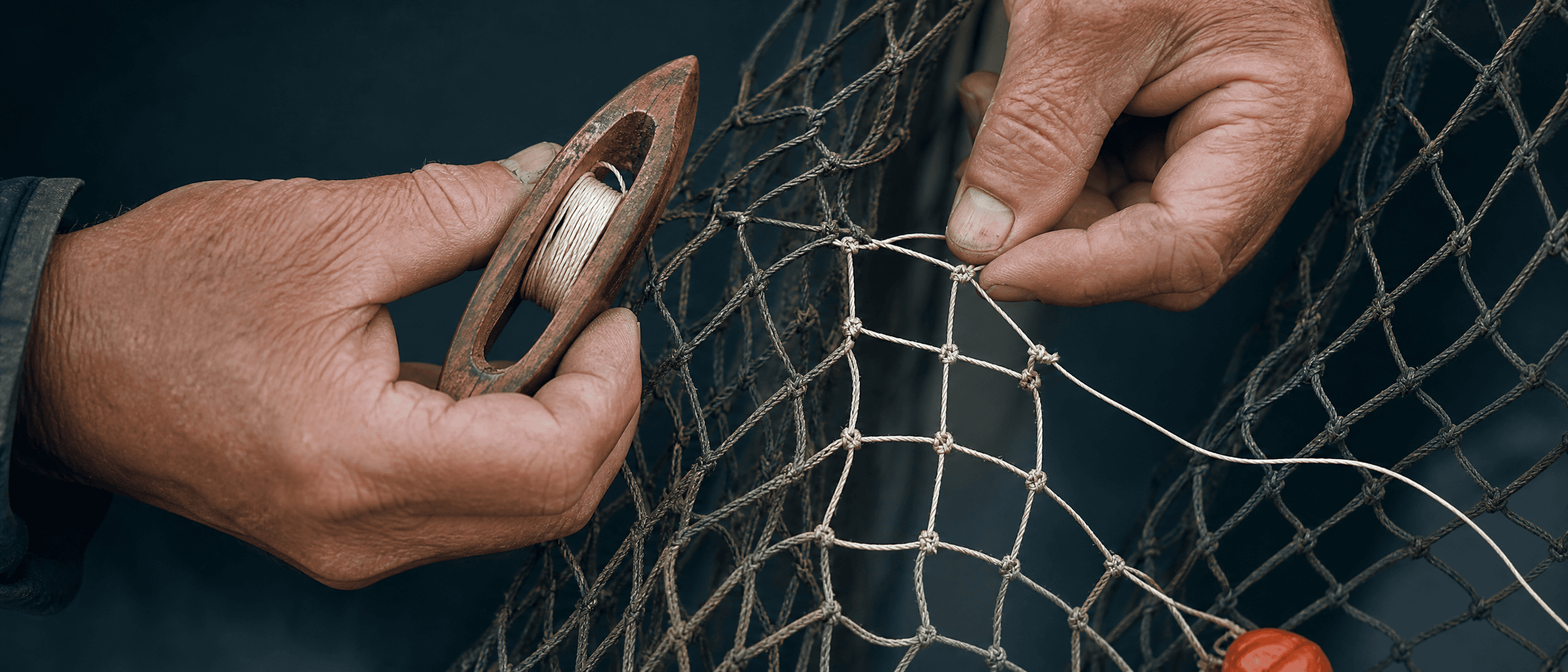 Deux mains remaillent un filet : le fil neuf, plus clair, entre dans les mailles anciennes et l on voit l endroit exact ou la reparation rejoint ce qui tenait deja.