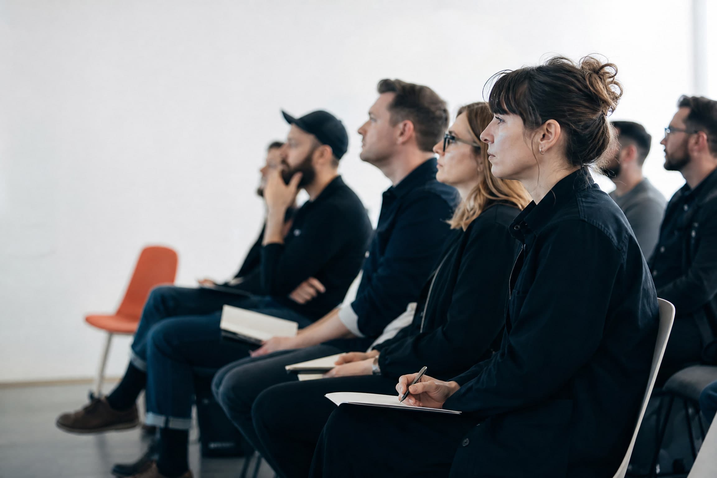 Des personnes assises en rangées, toutes tournées dans la même direction vers quelque chose hors du cadre.